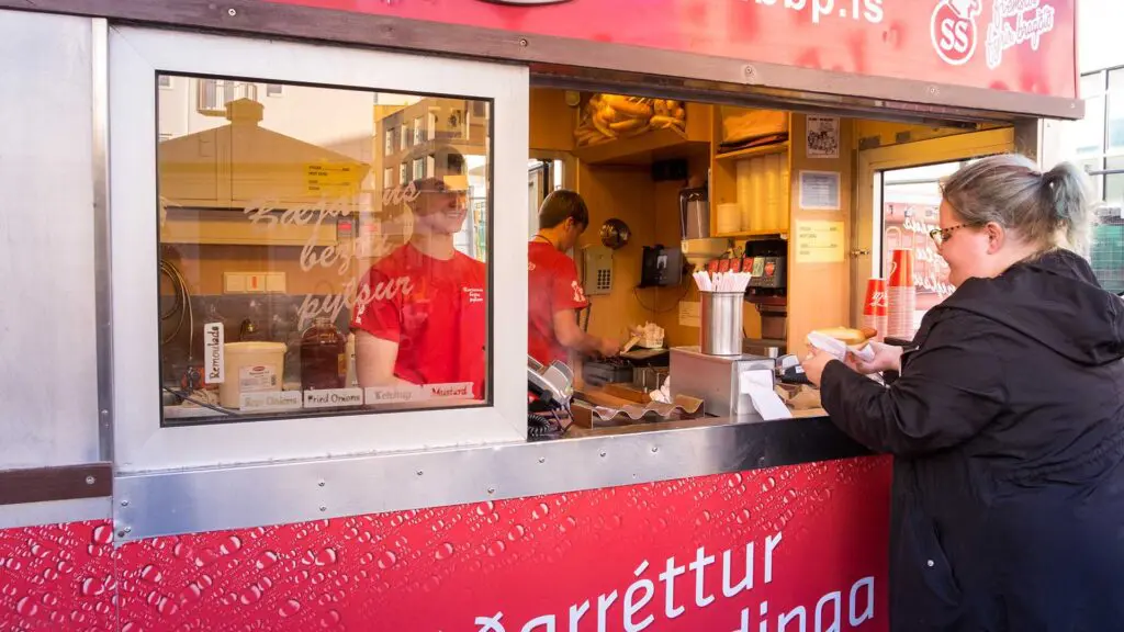 Woman buying food from red food truck in Reykjavik