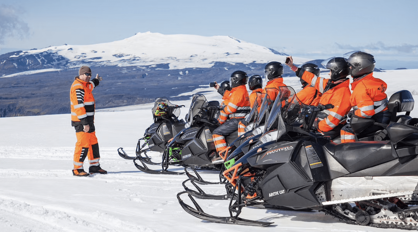 Guide with tourists on the snowmobile tour