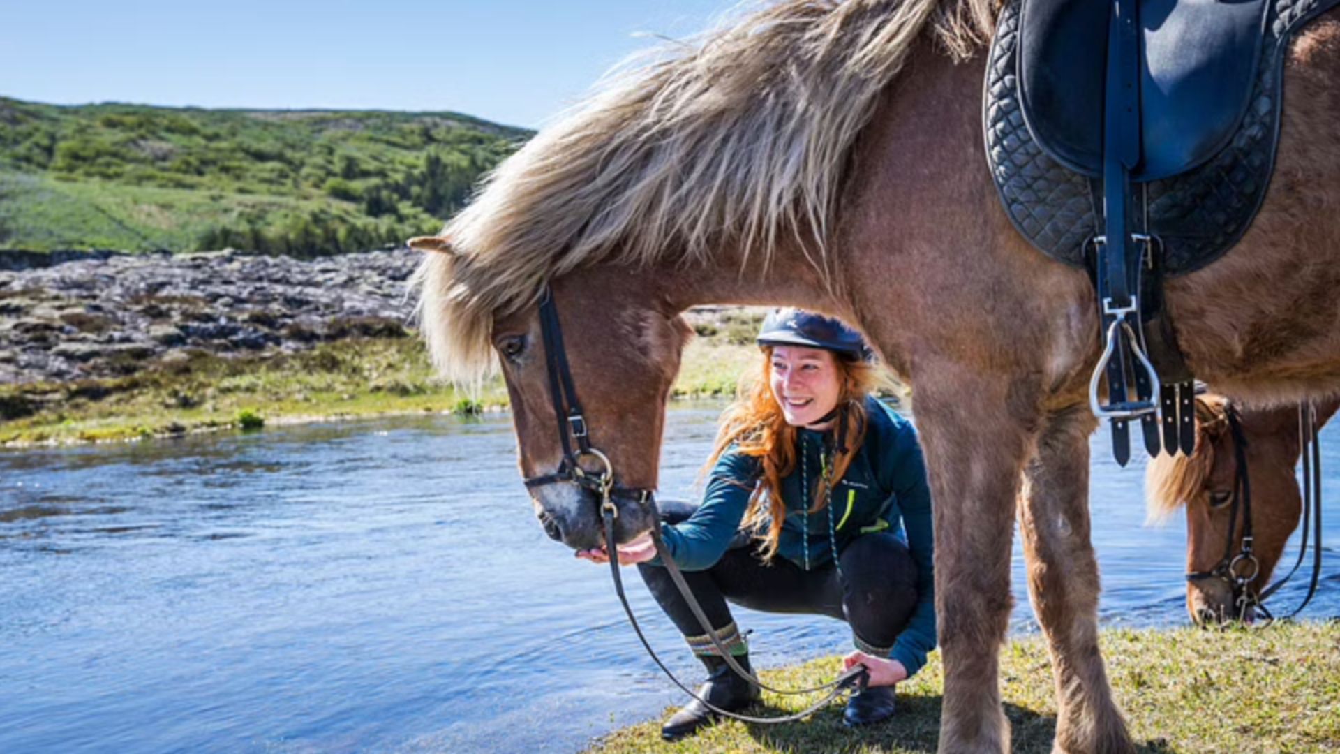 Tourist with the Icelandic horse near a river during the tour