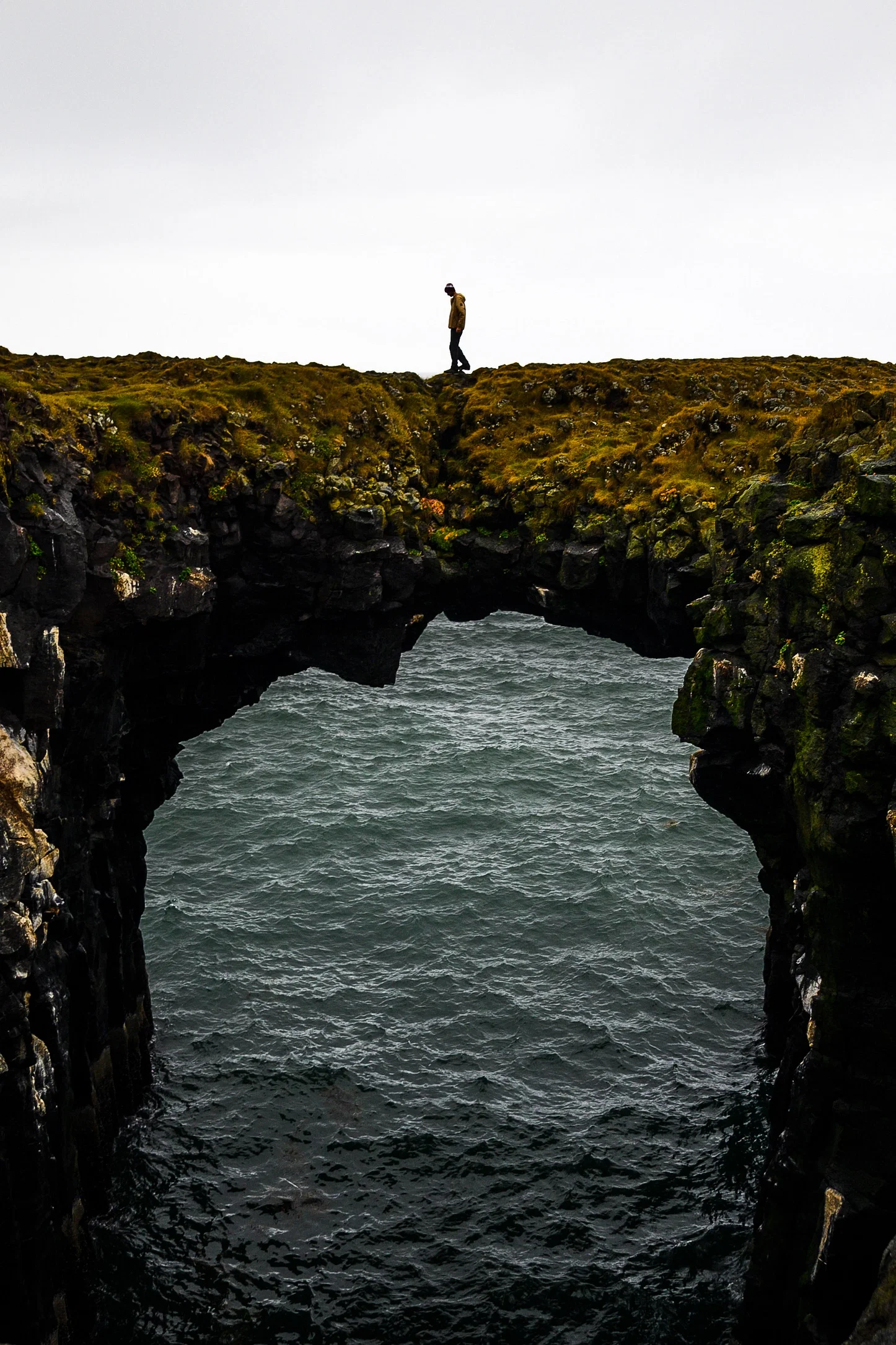Traveller walking over a rock formation that suspends over the ocean