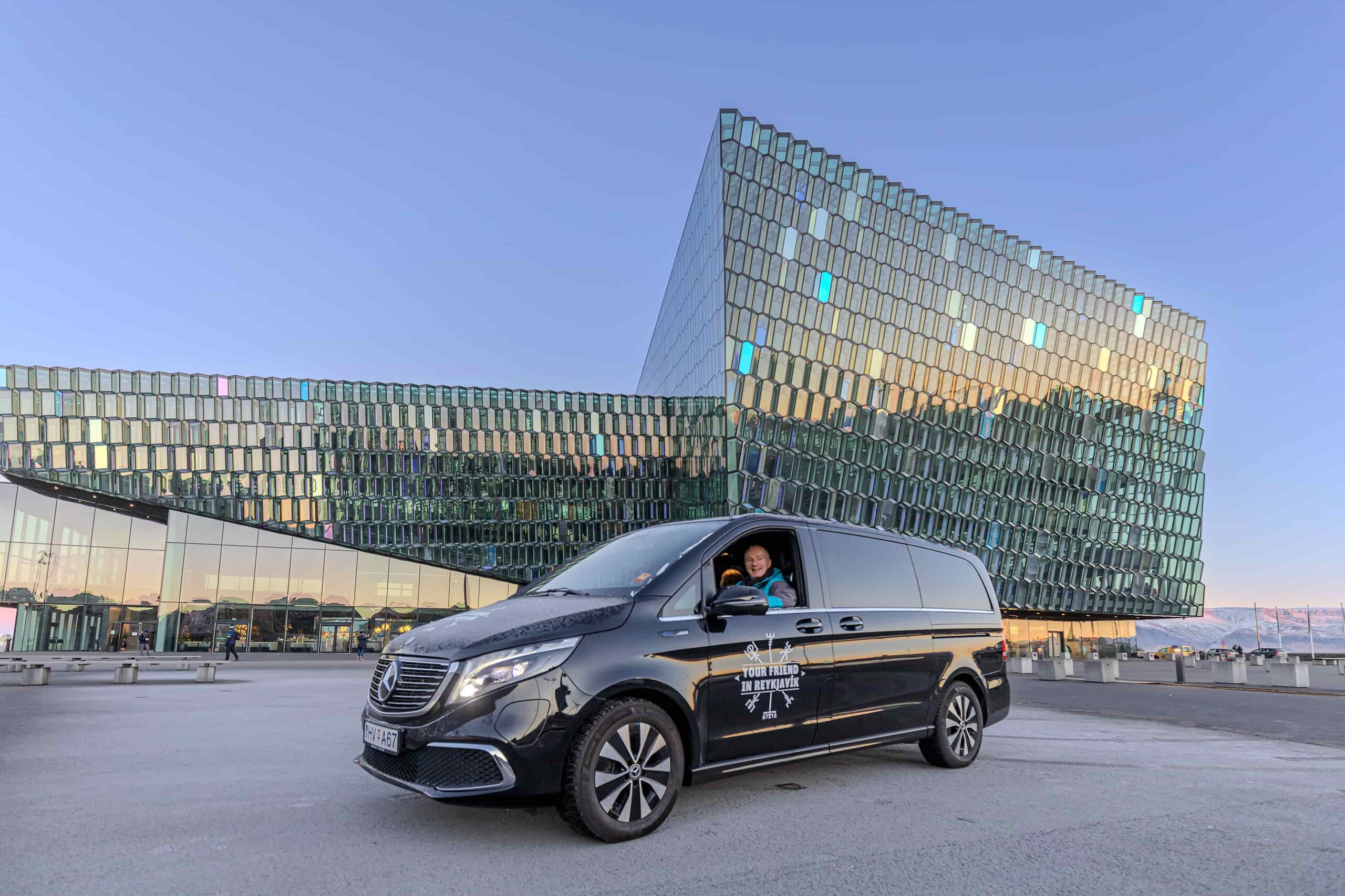A tour vehicle from Your Friend in Reykjavik in front of the Harpa Concert Hall