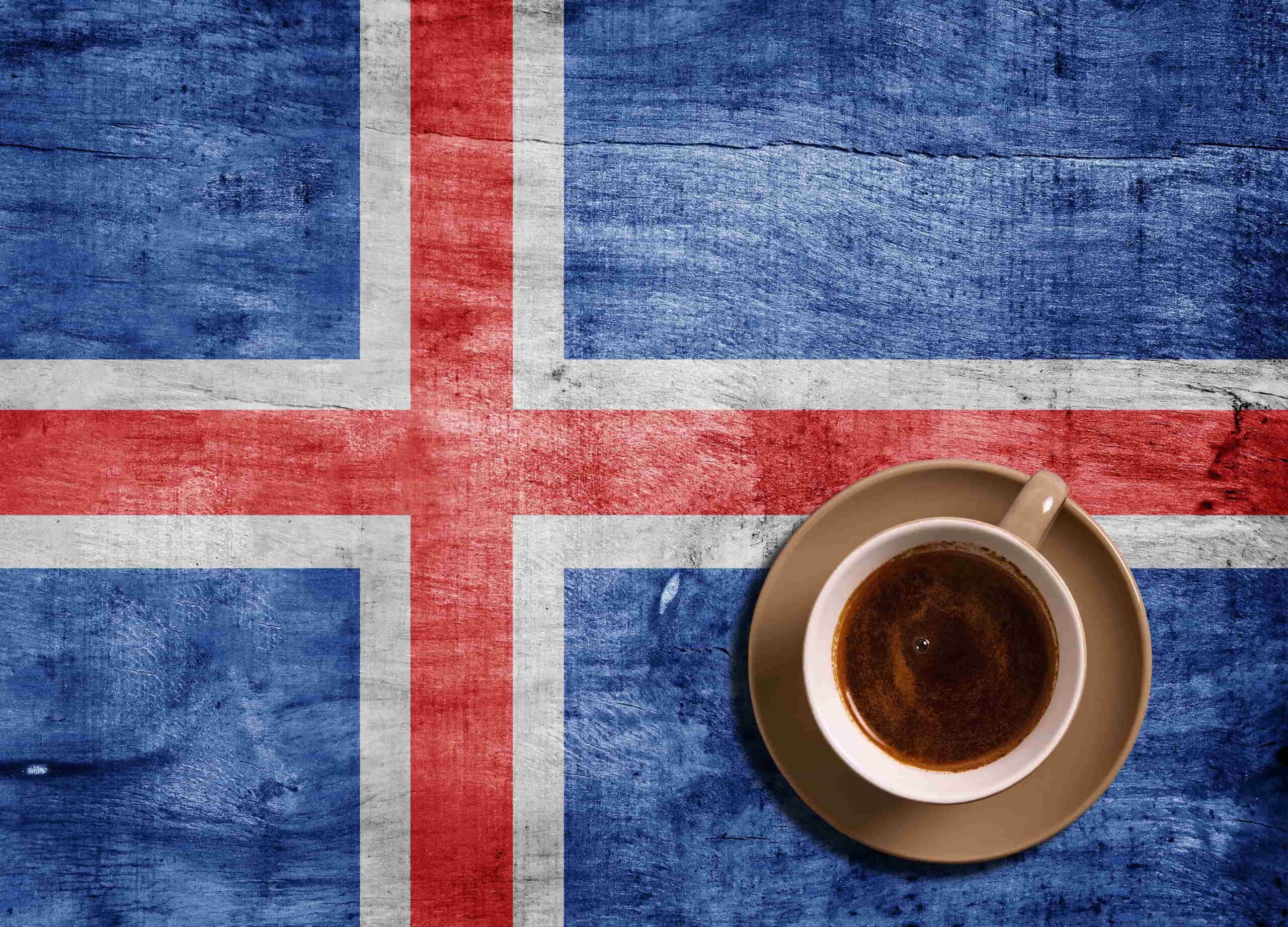 A flag of Iceland with a cup of coffee next to it.