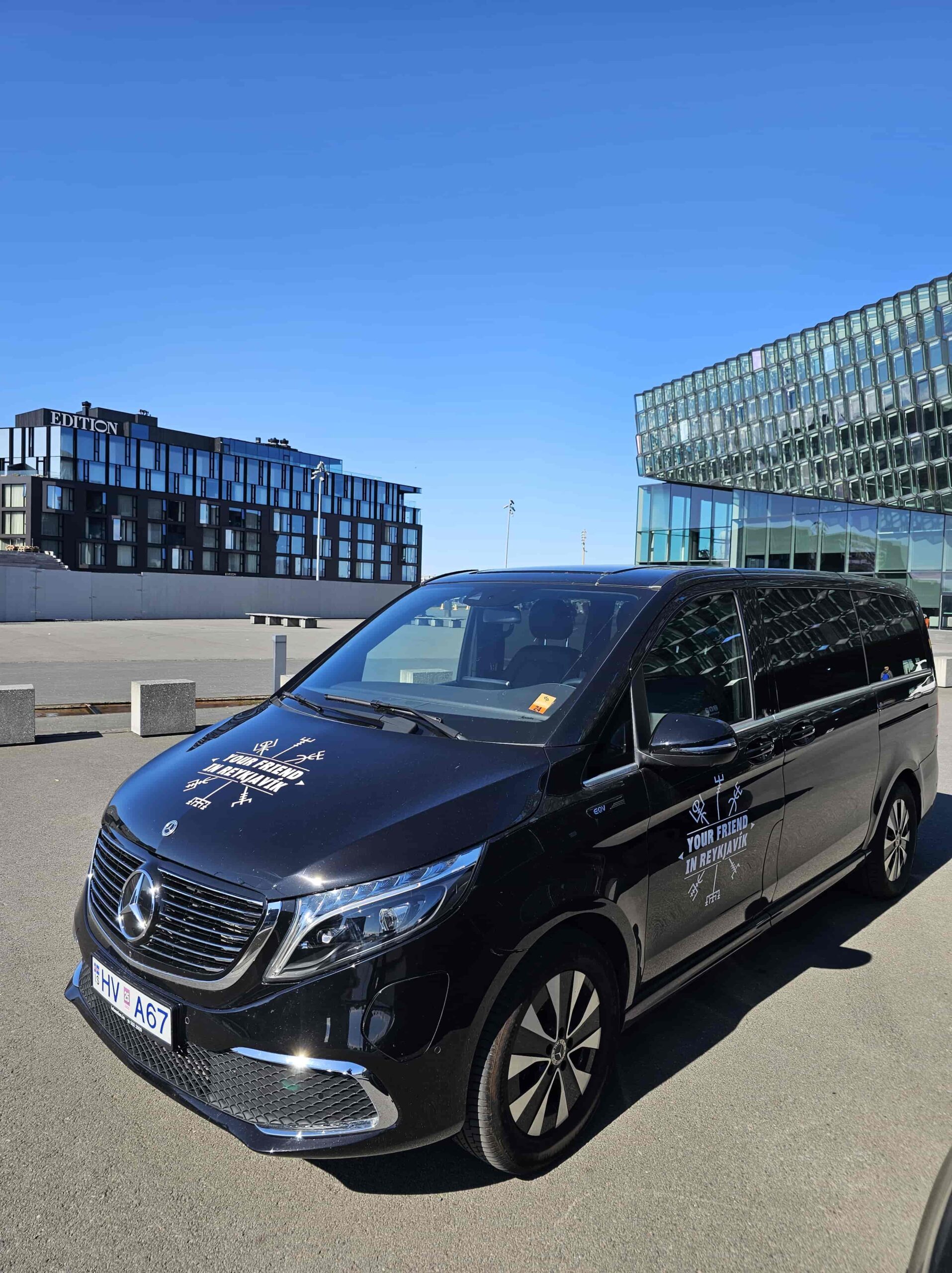 A luxurious tour vehicle from Your Friend in Reykjavik parked in front of the Harpa Concert Hall