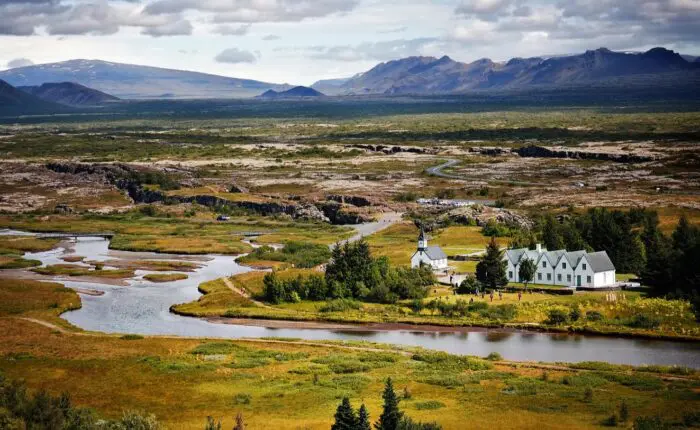 A large, open landscape with a river flowing through and some small houses