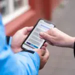 Two people navigating a browser on a phone