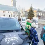 People standing around a black van with the Your Friend in Reykjavik logo displayed on it.