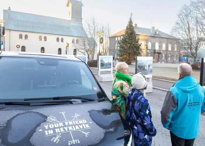 People standing around a black van with the Your Friend in Reykjavik logo displayed on it.