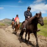 People riding horses along a dirt trail