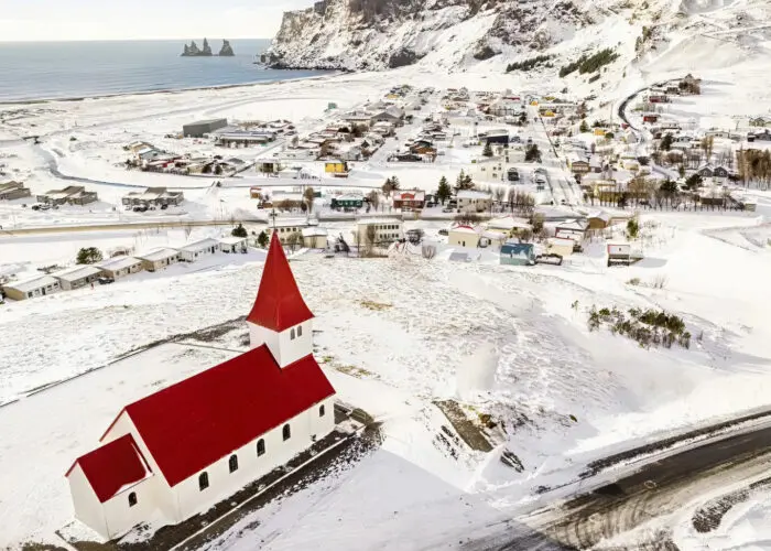 Vík í Mýrdal looks serene in winter, blanketed in snow with the southern coast’s rugged beauty