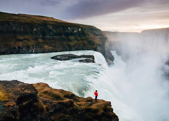 A woman stands before the cascading waters of Gulfoss, taking in the beauty of this historic site