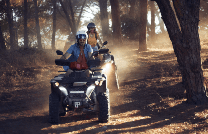 ATV Quad Bike Tour from Húsafell5-min Two people riding separate ATVs through a forested trail in Iceland