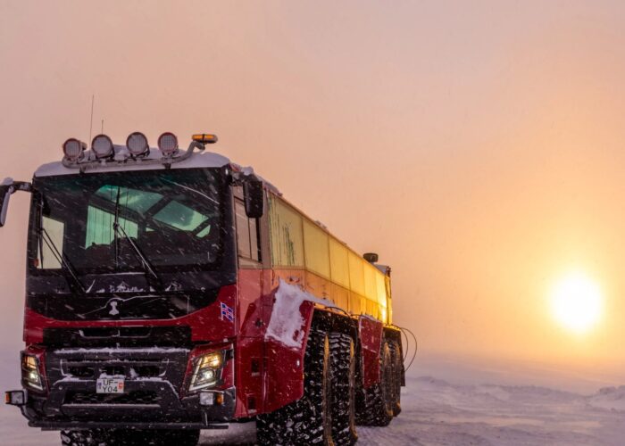 Monster truck bus out in the glaciers with the sun setting.
