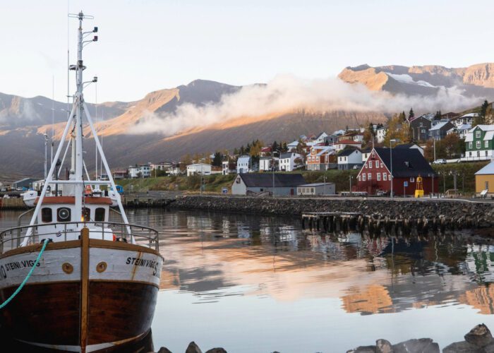 Boats docked in Siglufjörður harbor with colorful buildings